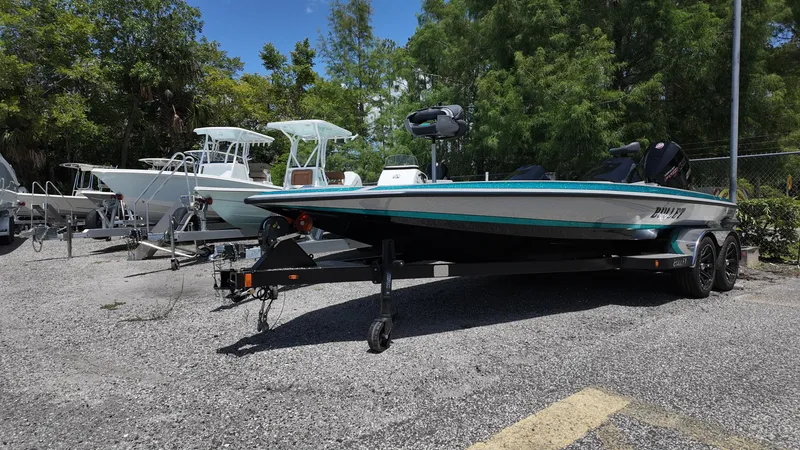 Slide: The Image of 2025 Bullet 21SDC boat on trailer in outdoor lot, surrounded by trees. - 2