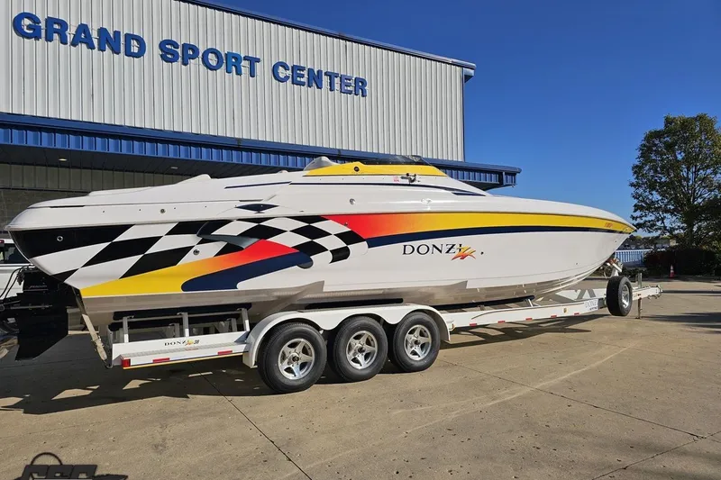 Slide: The Image of 2003 Donzi 38 ZX speedboat on trailer at Grand Sport Center, featuring vibrant racing graphics. - 10