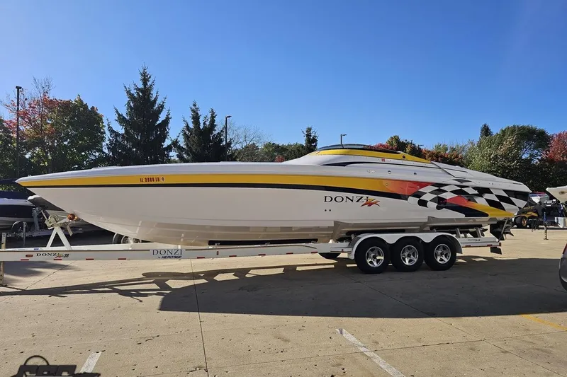 Slide: The Image of 2003 Donzi 38 ZX speedboat on trailer, vibrant graphics, parked outdoors. - 19