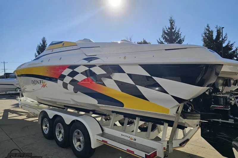 Slide: The Image of 2003 Donzi 38 ZX powerboat with vibrant graphics on a trailer, under clear blue sky. - 25