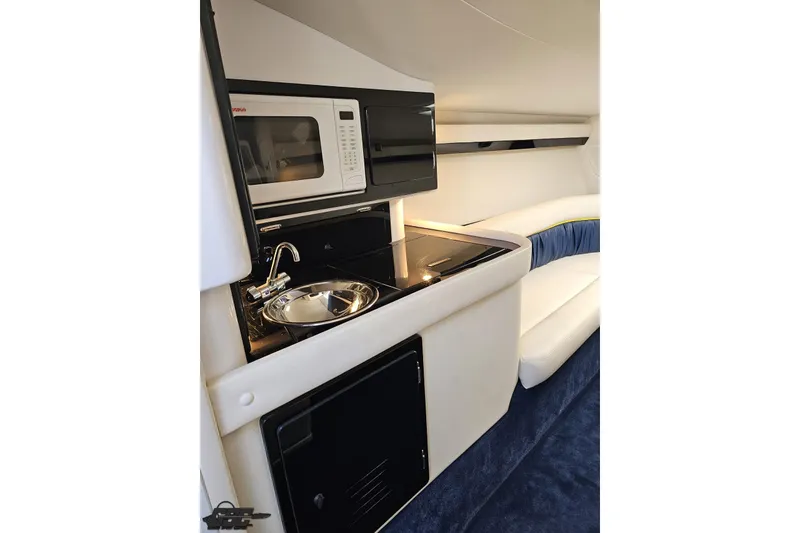 Slide: The Image of 2003 Donzi 38 ZX interior with kitchenette, featuring a microwave, sink, and seating area. - 67