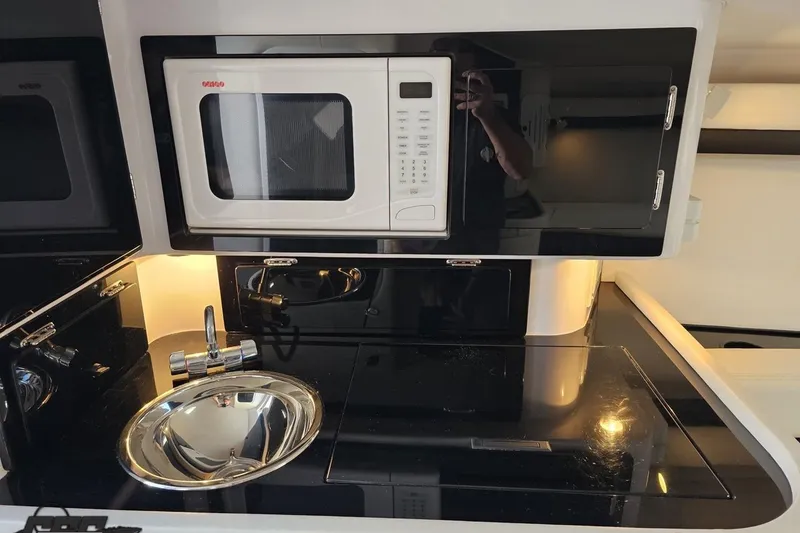 Slide: The Image of 2003 Donzi 38 ZX boat kitchenette with microwave, sink, and sleek black cabinetry. - 71