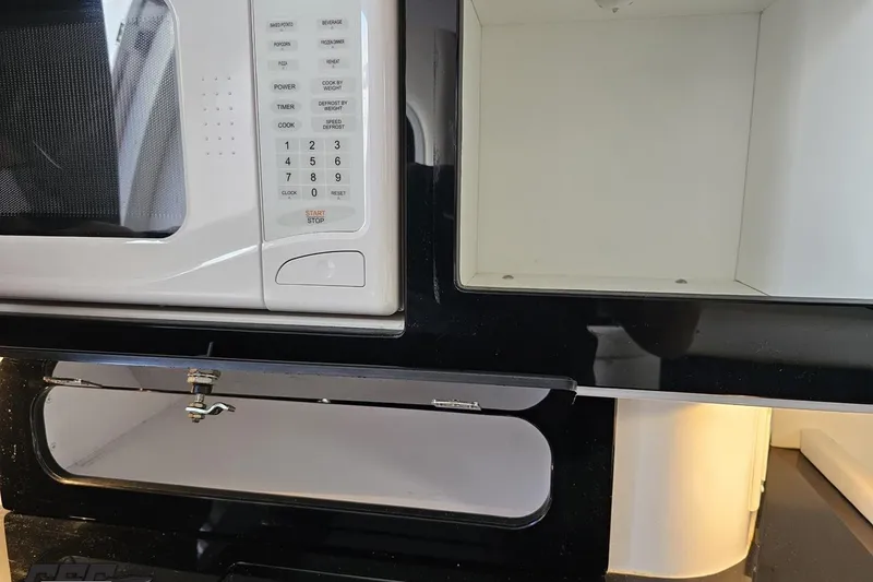 Slide: The Image of Microwave and storage compartment inside a 2003 Donzi 38 ZX boat kitchen area. - 74