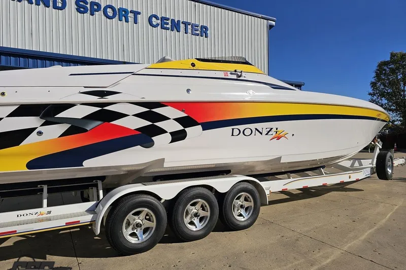 Slide: The Image of 2003 Donzi 38 ZX speedboat with vibrant graphics on a trailer outside a sport center. - 9