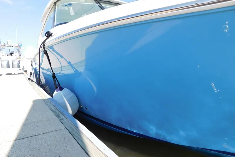 Slide: The Image of 2024 Pursuit DC 326 Dual Console boat docked with blue hull and fender. - 10