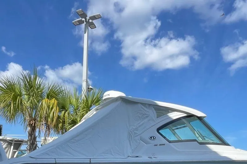 Slide: The Image of 2024 Pursuit DC 326 Dual Console boat under clear blue sky with palm trees. - 100