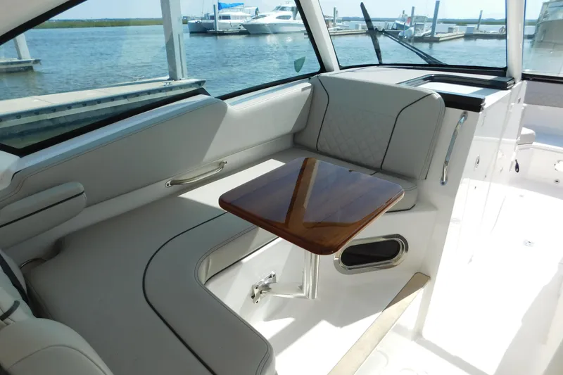 Slide: The Image of 2024 Pursuit DC 326 Dual Console interior with elegant seating and wooden table. - 28