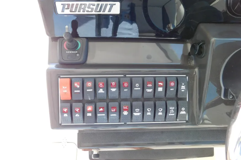 Slide: The Image of Control panel of 2024 Pursuit DC 326 Dual Console boat with various switches and joystick. - 37