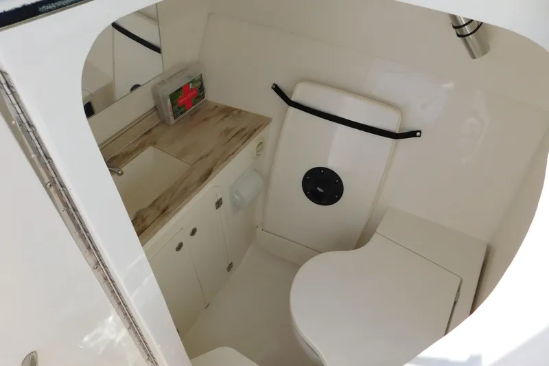 Slide: The Image of 2024 Pursuit DC 326 Dual Console boat bathroom with sink, toilet, and first aid kit. - 64