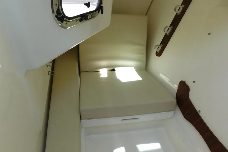 Slide: The Image of 2024 Pursuit DC 326 Dual Console cabin interior with cushioned seating and porthole window. - 74