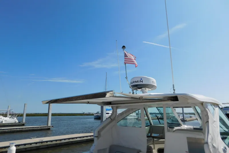 Slide: The Image of 2024 Pursuit DC 326 Dual Console boat docked with American flag and Garmin radar. - 87