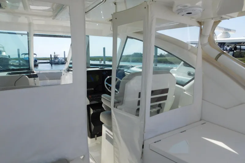 Slide: The Image of 2024 Pursuit DC 326 Dual Console interior with helm and seating, docked by the water. - 95