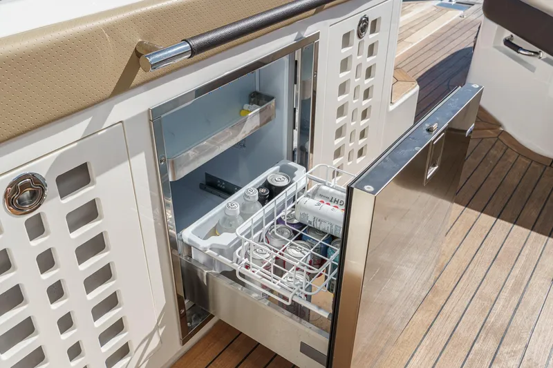 Slide: The Image of 2023 Sea Ray SLX 400 Outboard boat with open stainless steel refrigerator drawer. - 17