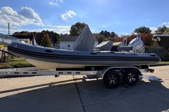 Slide: The Image of 2027 Brig Navigator 610 boat on trailer, parked outdoors under a partly cloudy sky. - 10