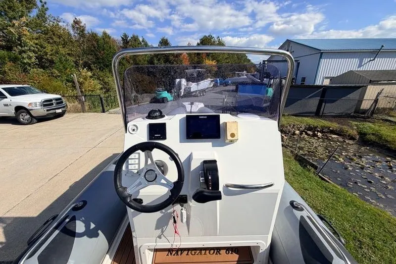 Slide: The Image of 2027 Brig Navigator 610 boat dashboard with steering wheel and controls. - 6
