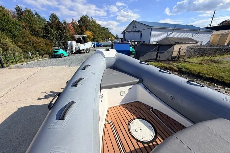 Slide: The Image of 2027 Brig Navigator 610 boat with wooden deck, parked outdoors on a sunny day. - 9