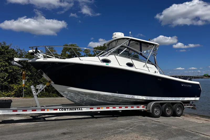 Slide: The Image of 2008 Sailfish 3006 boat on trailer under clear blue sky. - 25