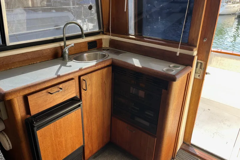 Slide: The Image of 1989 Bayliner 3888 MY Sedan boat interior kitchen with sink and wooden cabinetry. - 10