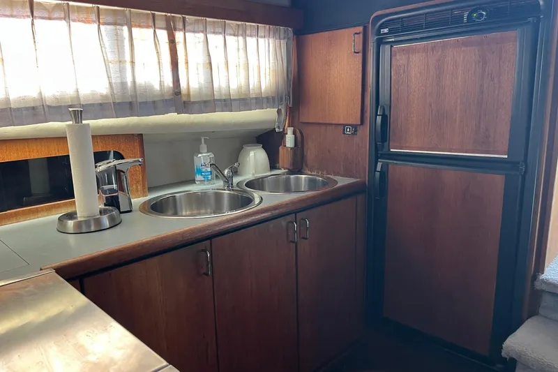 Slide: The Image of 1989 Bayliner 3888 MY Sedan kitchen with dual sinks and wooden cabinetry. - 9