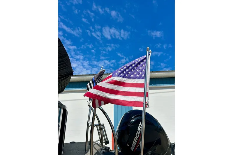 Slide: The Image of 2024 Barletta ARIA 22QC boat with American flags and Mercury engine under blue sky. - 10