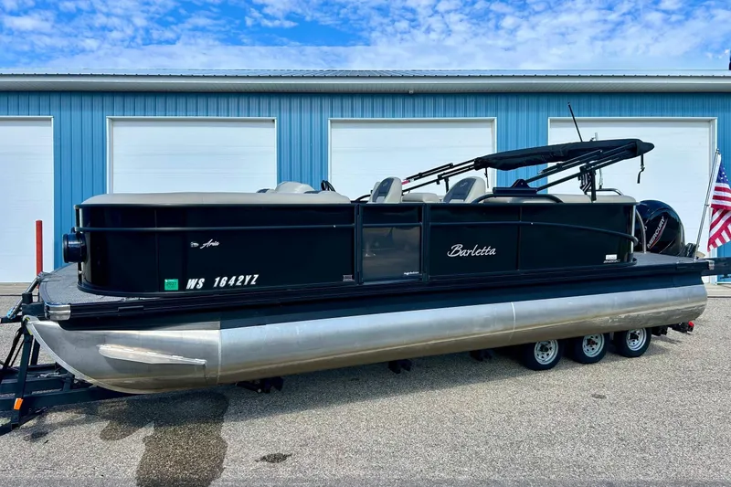 Slide: The Image of 2024 Barletta ARIA 22QC pontoon boat on trailer, parked by blue building. - 69