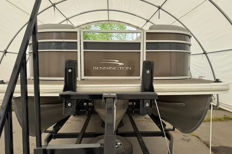Slide: The Image of 2023 Bennington 23SSR pontoon boat in storage, front view under canopy. - 2