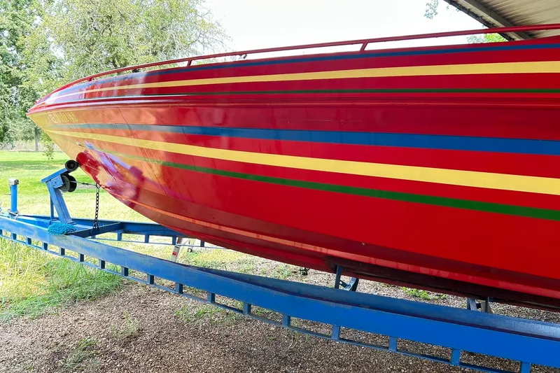 Slide: The Image of 1987 Chris-Craft 312 Stinger boat with vibrant red and multicolored stripes on a blue trailer. - 15