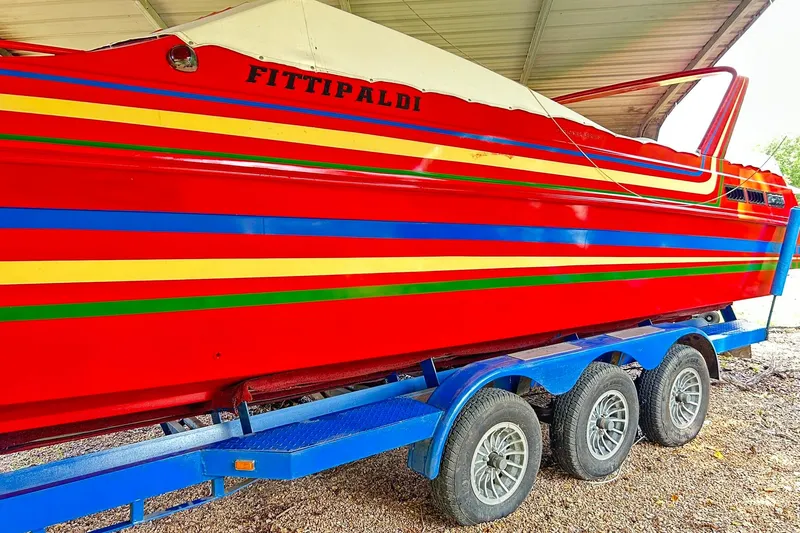 Slide: The Image of 1987 Chris-Craft 312 Stinger boat with vibrant red, blue, and yellow stripes on a blue trailer. - 16