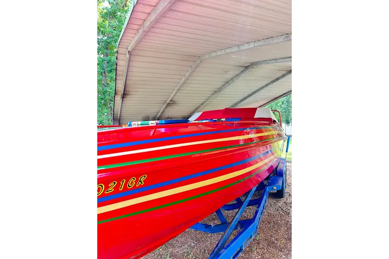 Slide: The Image of 1987 Chris-Craft 312 Stinger boat with vibrant red and striped design under a canopy. - 18
