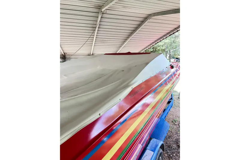 Slide: The Image of 1987 Chris-Craft 312 Stinger boat with colorful stripes under a metal canopy. - 19
