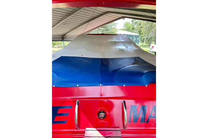 Slide: The Image of 1987 Chris-Craft 312 Stinger boat under a shelter with a colorful cover. - 20