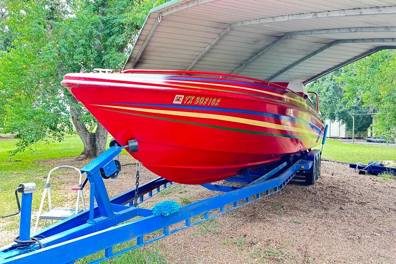 Slide: The Image of 1987 Chris-Craft 312 Stinger boat, vibrant red, on a blue trailer under a metal canopy. - 50