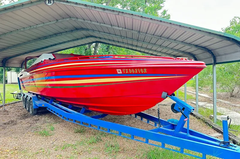 Slide: The Image of 1987 Chris-Craft 312 Stinger boat in vibrant red under a metal canopy. - 52
