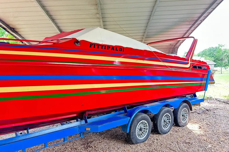 Slide: The Image of 1987 Chris-Craft 312 Stinger boat with vibrant red and striped design on a blue trailer. - 8