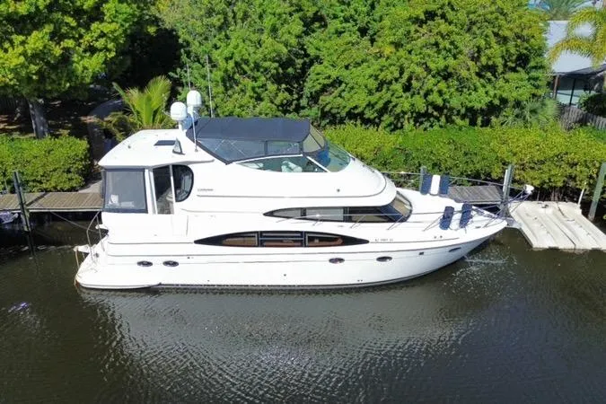 The Image of 2004 Carver 466 Motor Yacht docked on a serene waterway, surrounded by lush greenery. - 0
