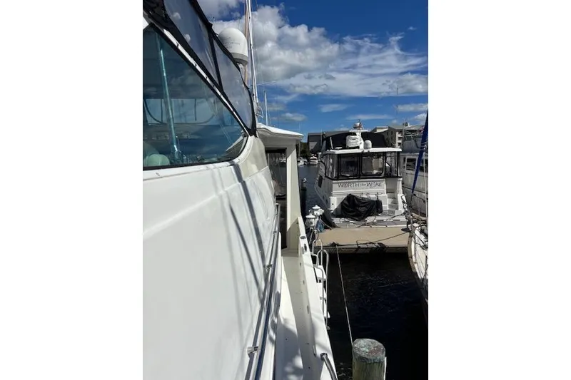 Slide: The Image of 2004 Carver 466 Motor Yacht side view with clear skies and marina background. - 37