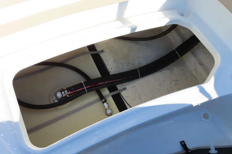 Slide: The Image of 2021 Hurricane SunDeck Sport 185 OB boat interior compartment with visible hoses and fittings. - 24