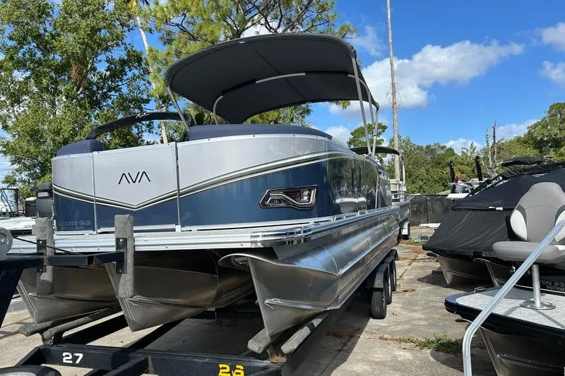 The Image of 2025 Avalon LSZ Quad Lounger Shift pontoon boat on trailer, under blue sky. - 0