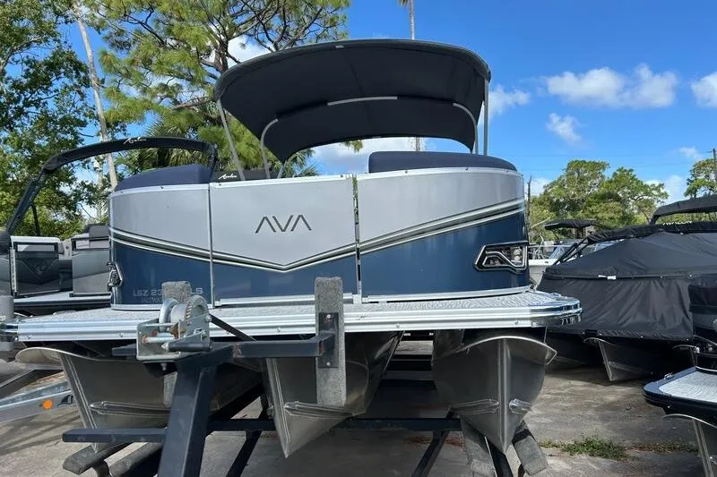 Slide: The Image of 2025 Avalon LSZ Quad Lounger Shift pontoon boat on trailer, under blue sky. - 4