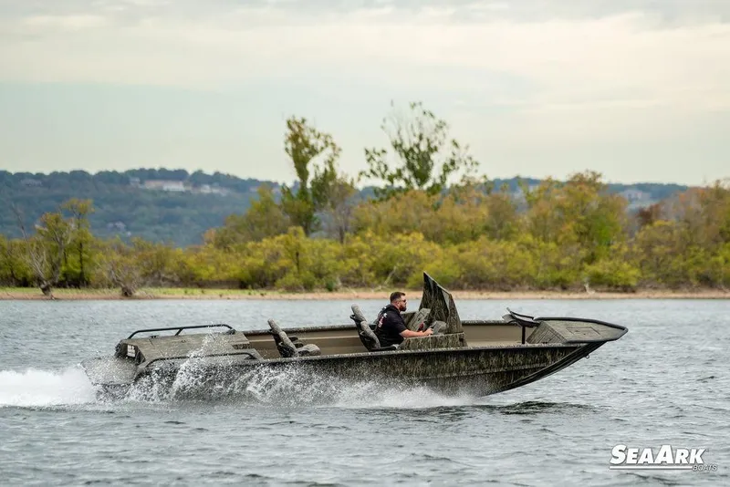 Slide: The Image of 2026 SeaArk Predator boat speeding on a lake with lush green shoreline. - 5