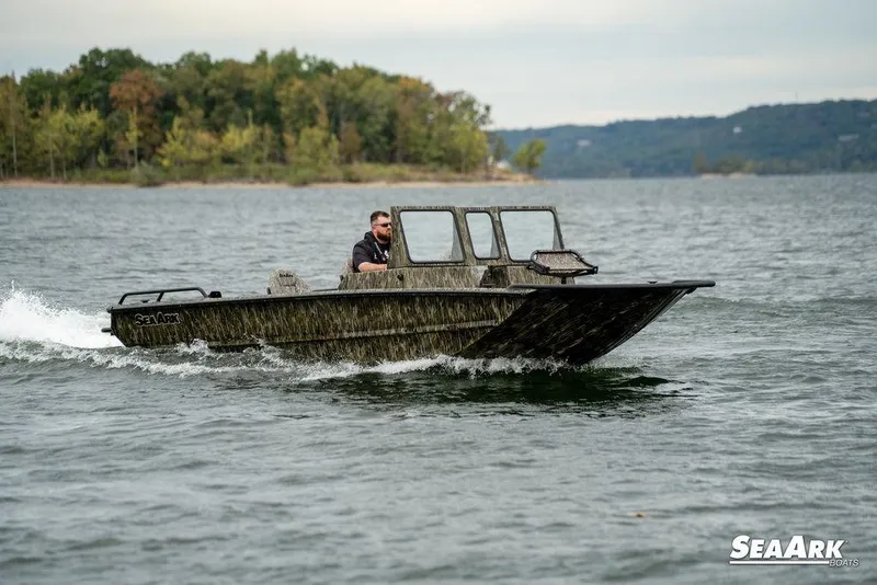 Slide: The Image of 2026 SeaArk Predator boat cruising on a lake with forested shoreline. - 9