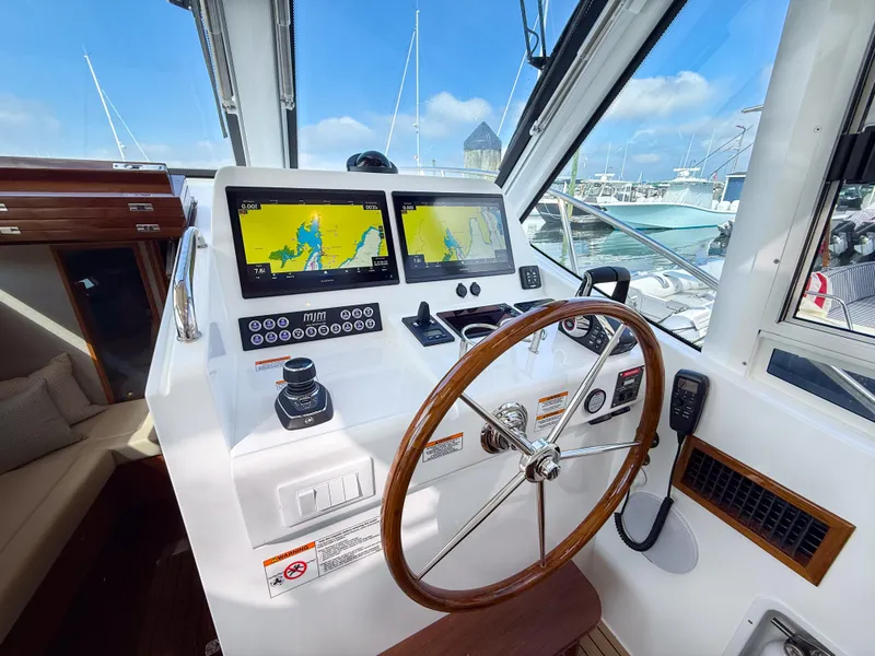 Slide: The Image of Helm of 2026 MJM 47R yacht with navigation screens and wooden steering wheel. - 2