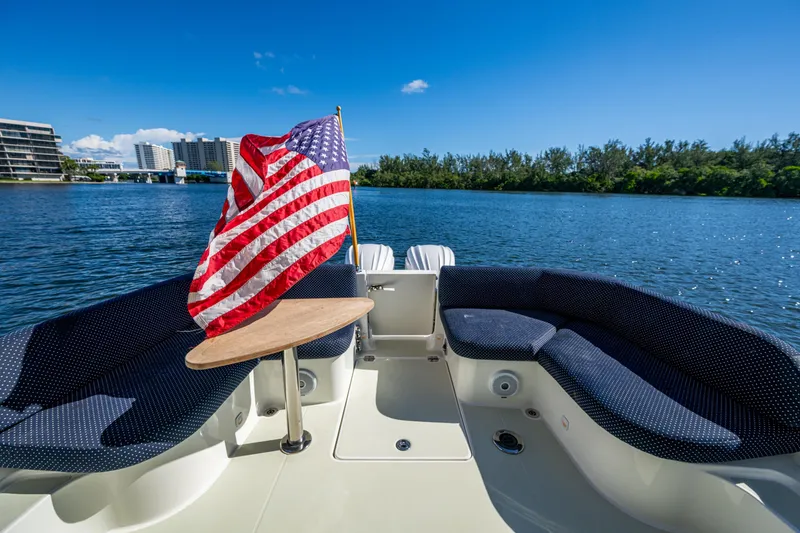 Slide: The Image of 2020 Back Cove 340 boat with American flag, spacious seating, and scenic waterfront view. - 22