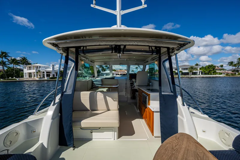 Slide: The Image of 2020 Back Cove 340 boat interior with seating, docked by waterfront homes. - 31