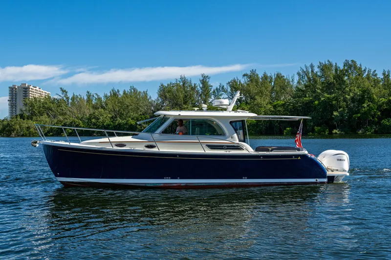 Slide: The Image of 2020 Back Cove 340 boat cruising on a serene waterway with lush greenery. - 40