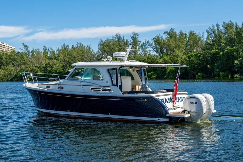 Slide: The Image of 2020 Back Cove 340 boat cruising on a serene lake with lush greenery. - 42