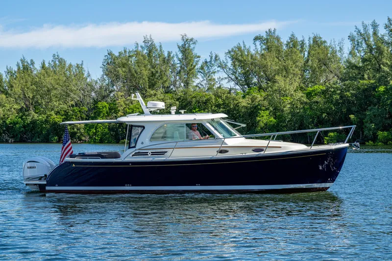 Slide: The Image of 2020 Back Cove 340 boat cruising on a serene lake with lush greenery. - 44