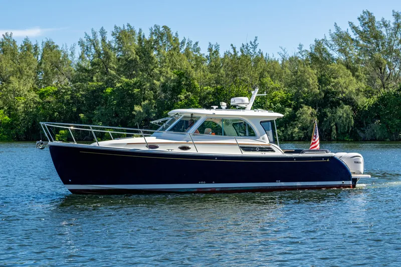 Slide: The Image of 2020 Back Cove 340 boat cruising on a serene lake with lush greenery. - 46