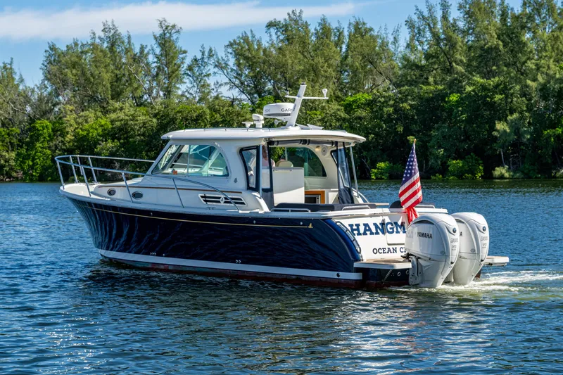 Slide: The Image of 2020 Back Cove 340 boat cruising on a scenic lake with lush greenery. - 48