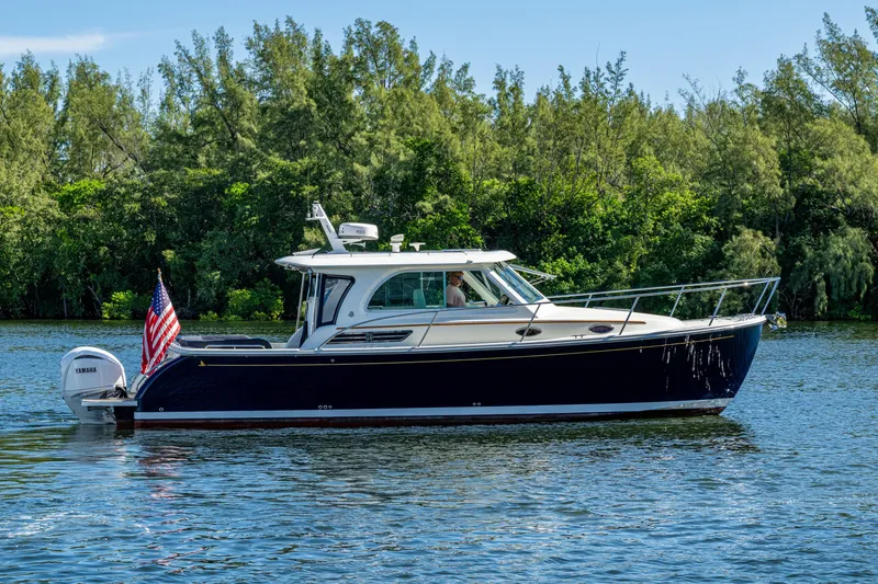 Slide: The Image of 2020 Back Cove 340 boat cruising on a serene lake with lush greenery. - 51